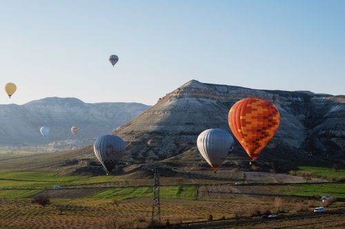 Free Vibrant hot air balloons soaring above Cappadocia's stunning terrain in daylight. Stock Photo
