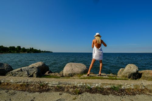 Free A woman in white enjoying the serene view of the Baltic Sea from Hara, Estonia on a sunny day. Stock Photo