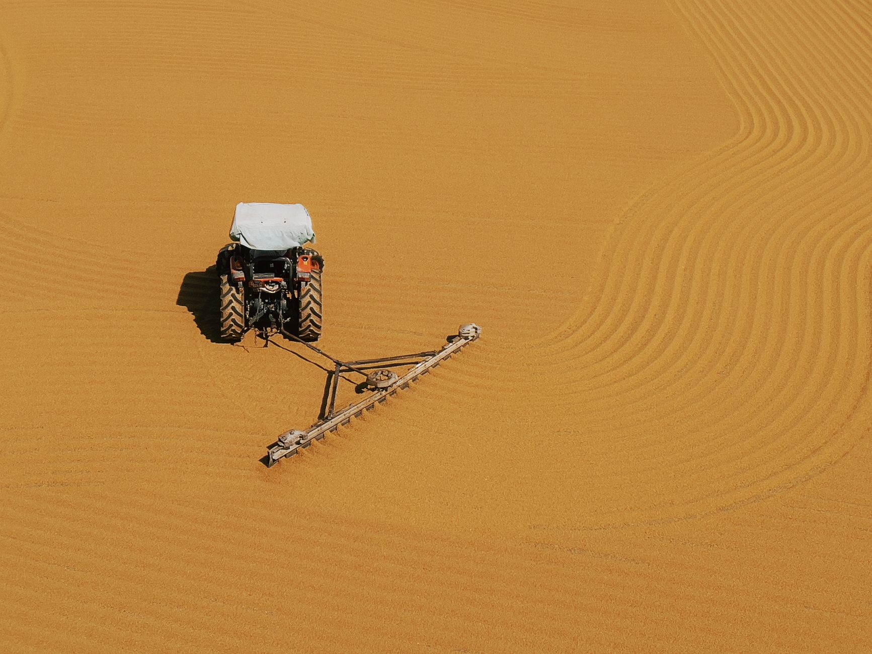 Aerial view of a tractor creating precise lines on a cultivated field.