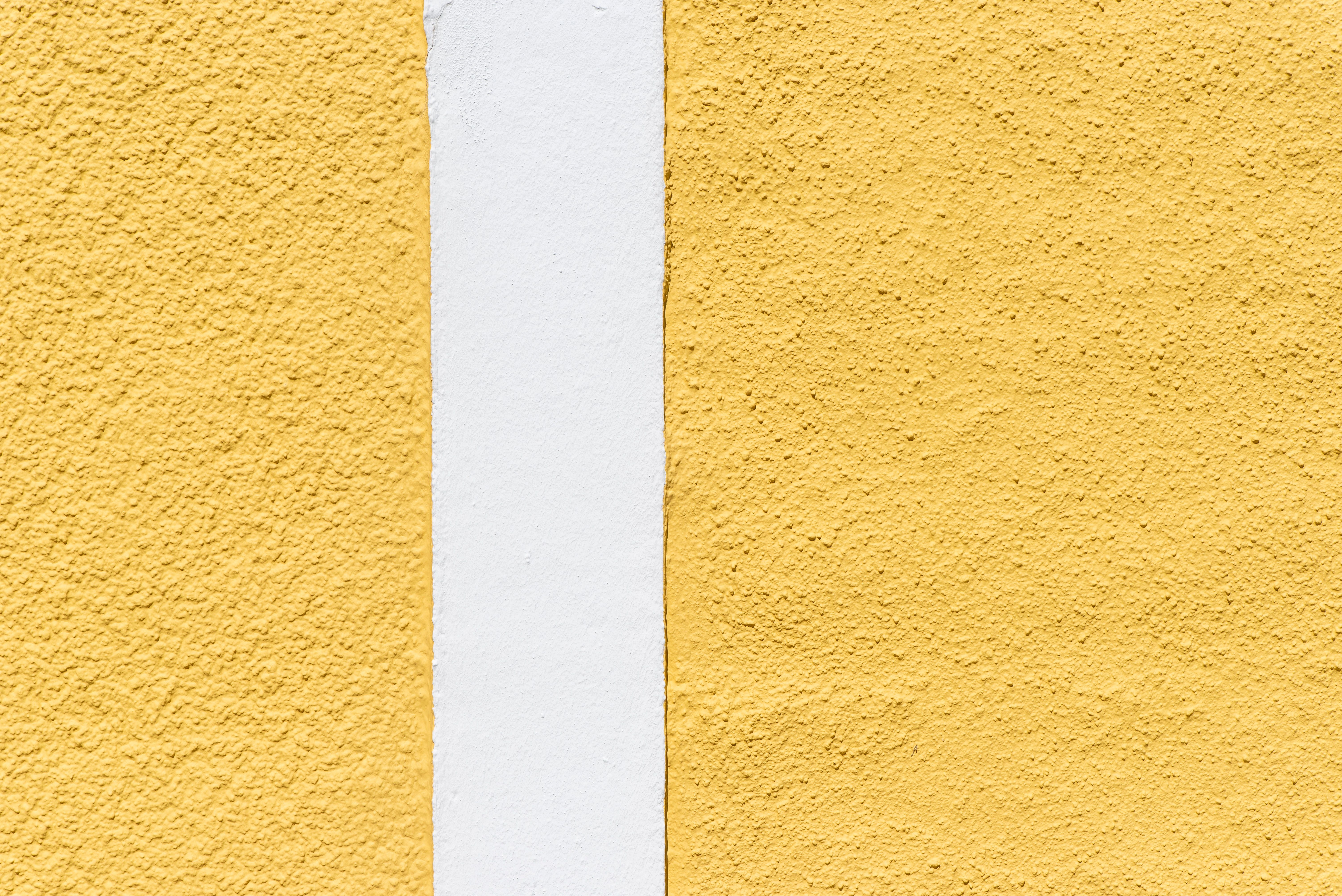 Minimalist close-up of a yellow and white textured wall with shadow play.