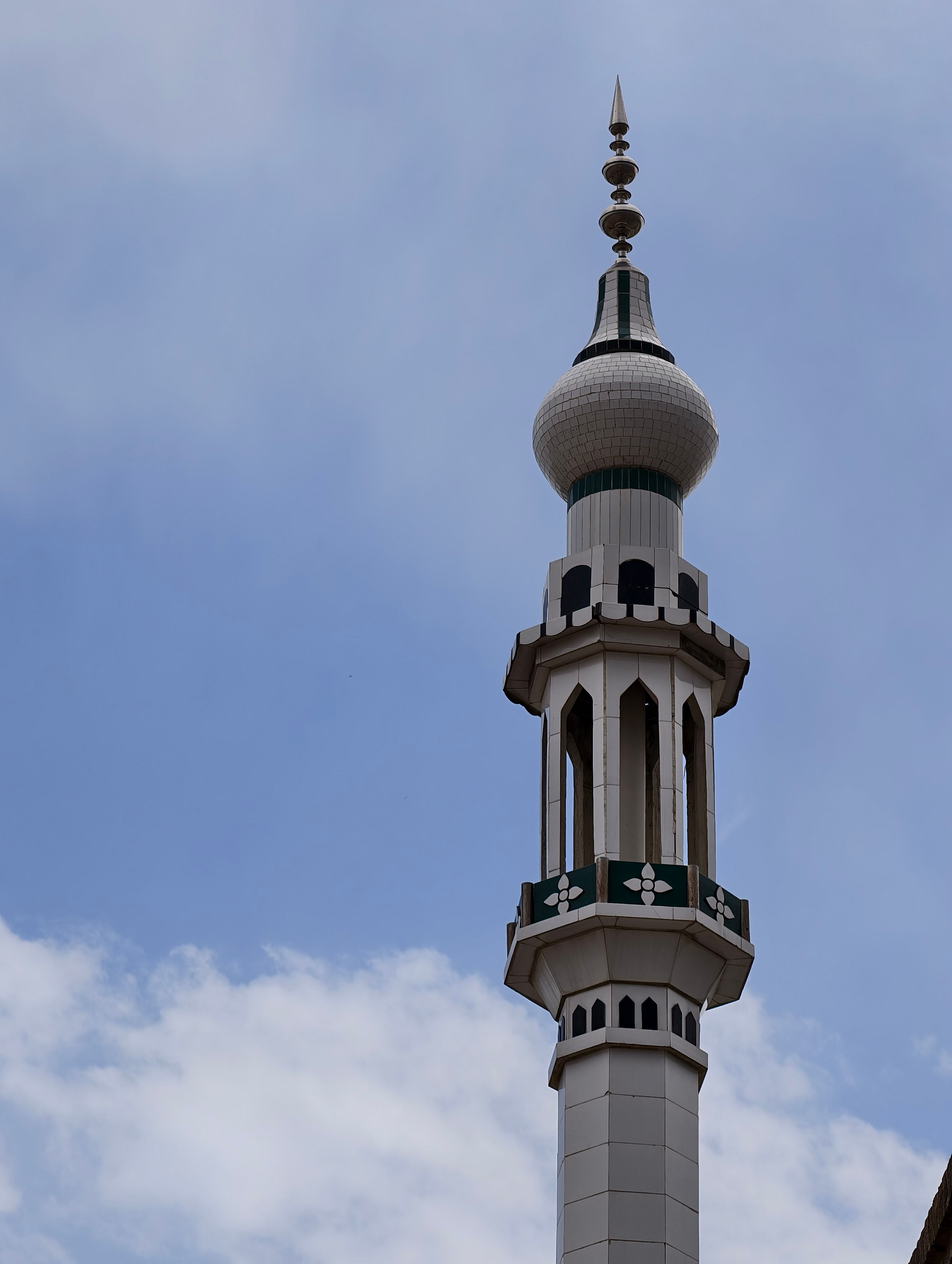 A tall mosque minaret with intricate designs set against a clear blue sky.