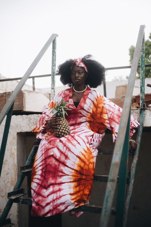 Free Portrait of a woman in vibrant Nigerian attire holding a pineapple, exuding elegance and cultural richness. Stock Photo