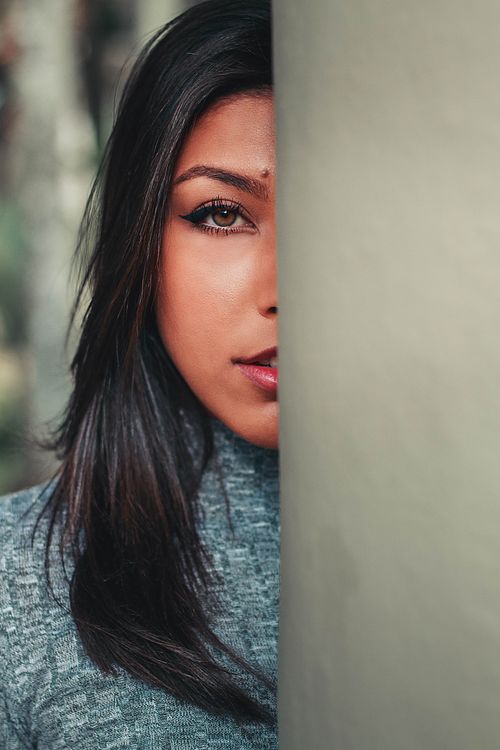 Free A woman partially hidden, gazing intently, creating a mysterious portrait. Stock Photo