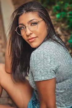 在户外环境中，一位戴着眼镜的优雅女性散发着自然的美丽与魅力