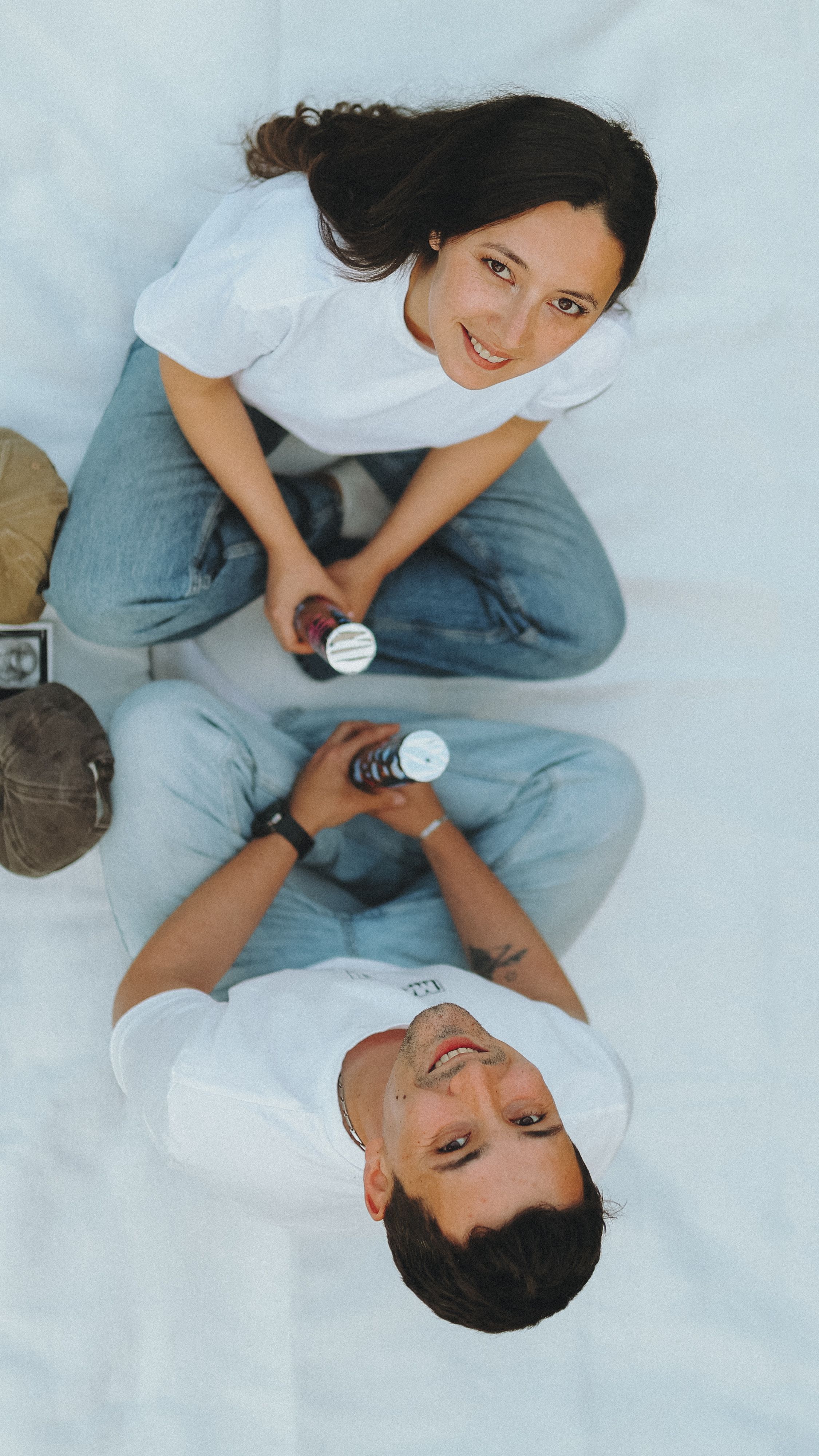 Happy couple sitting indoors, looking up at the camera with a cheerful expression.