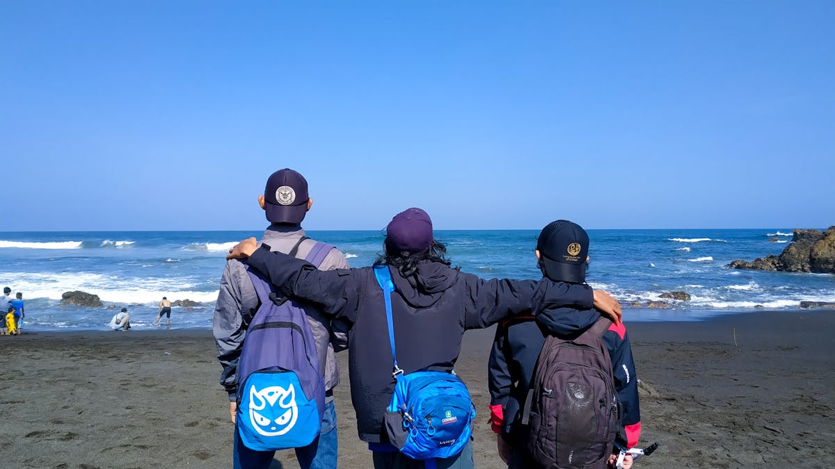Hands assembling a colorful grain bowl with vegetables and beans