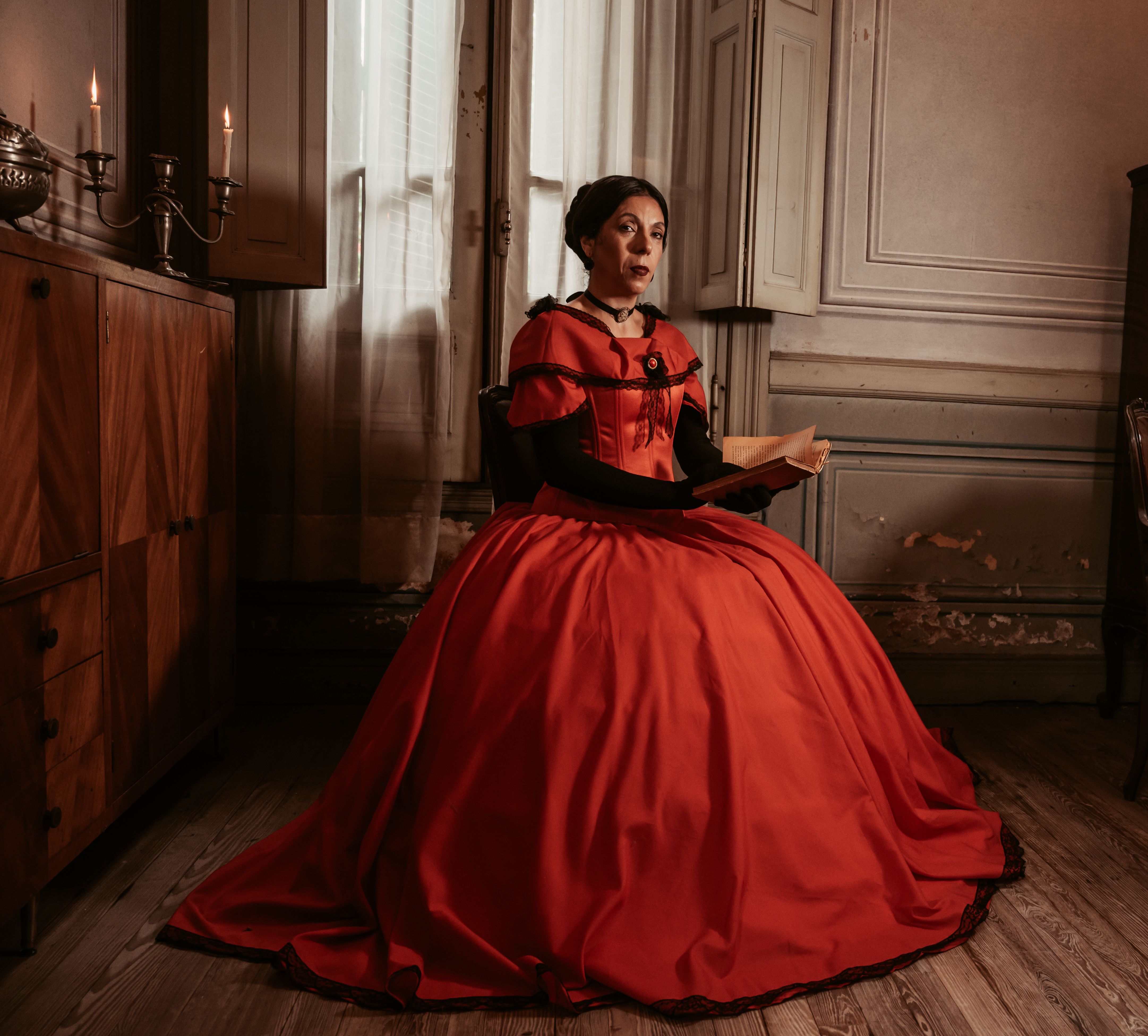 Victorian woman in red gown seated, capturing elegance and historical charm.