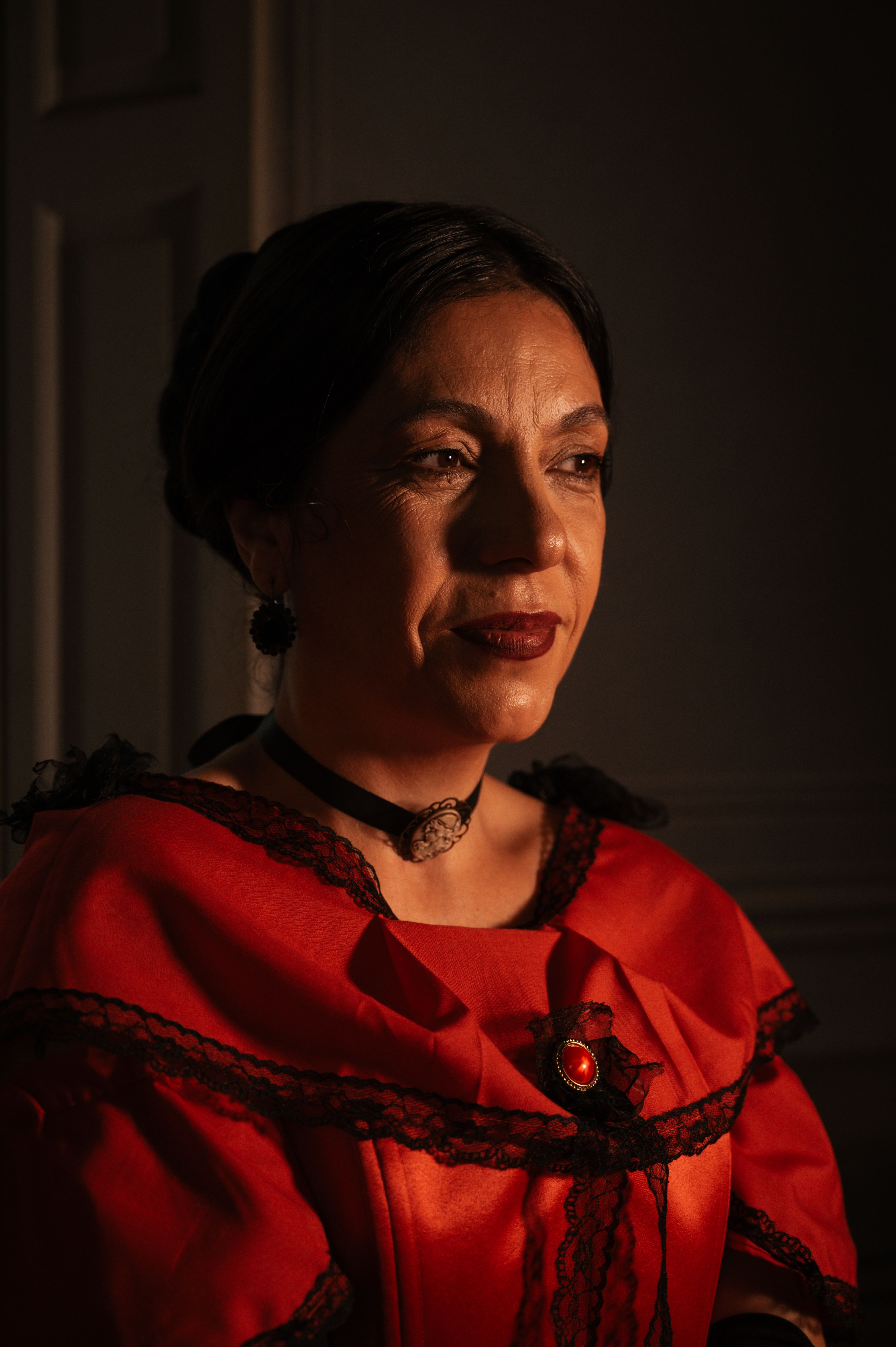 Captivating portrait of a woman in a vintage red costume with dramatic lighting.