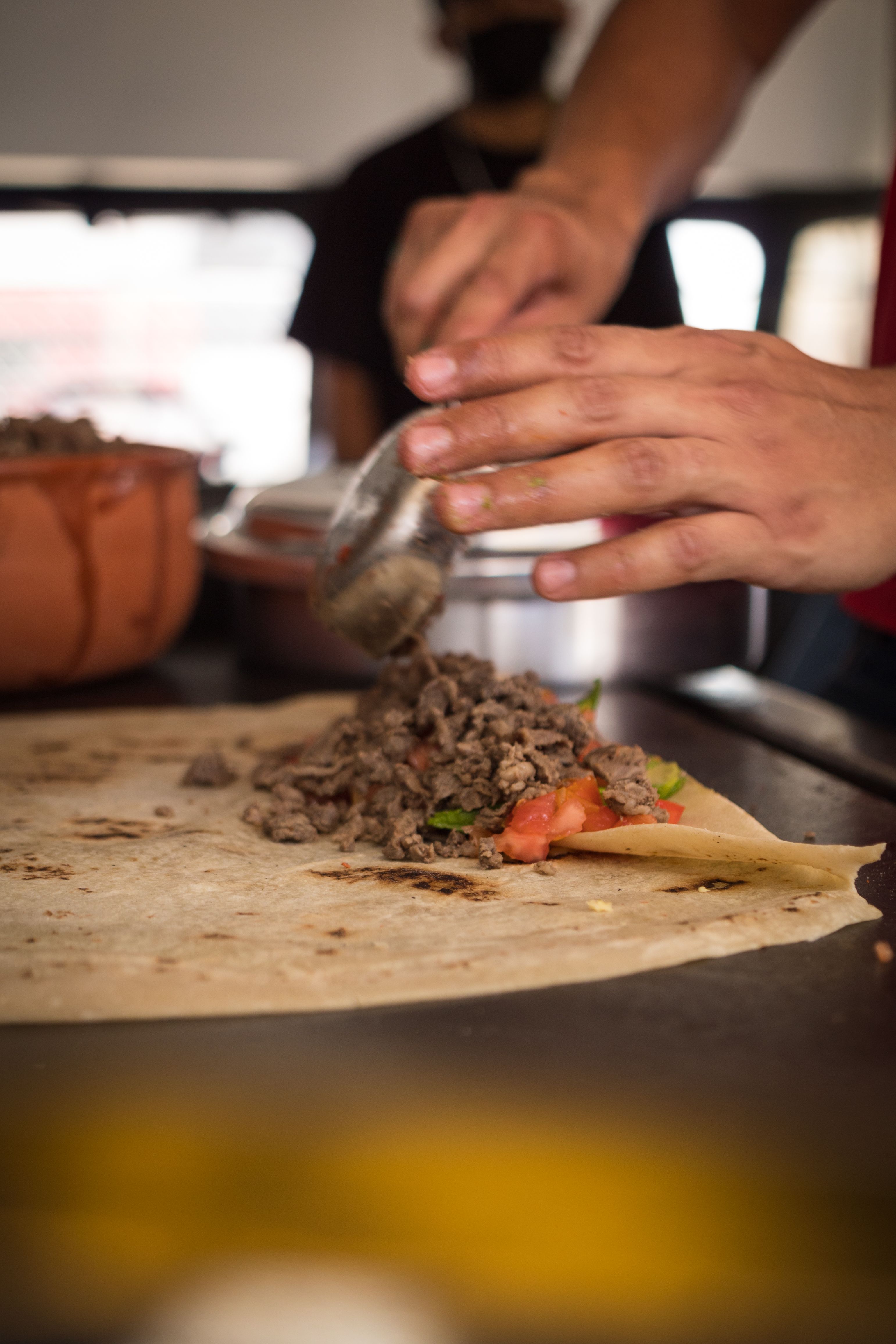 Close-up of a traditional Mexican burrito being prepared with beef and vegetables.