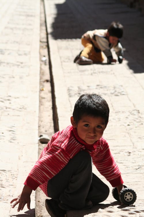 бесплатная Мальчик в красной рубашке с длинным рукавом и черных брюках Стоковое фото