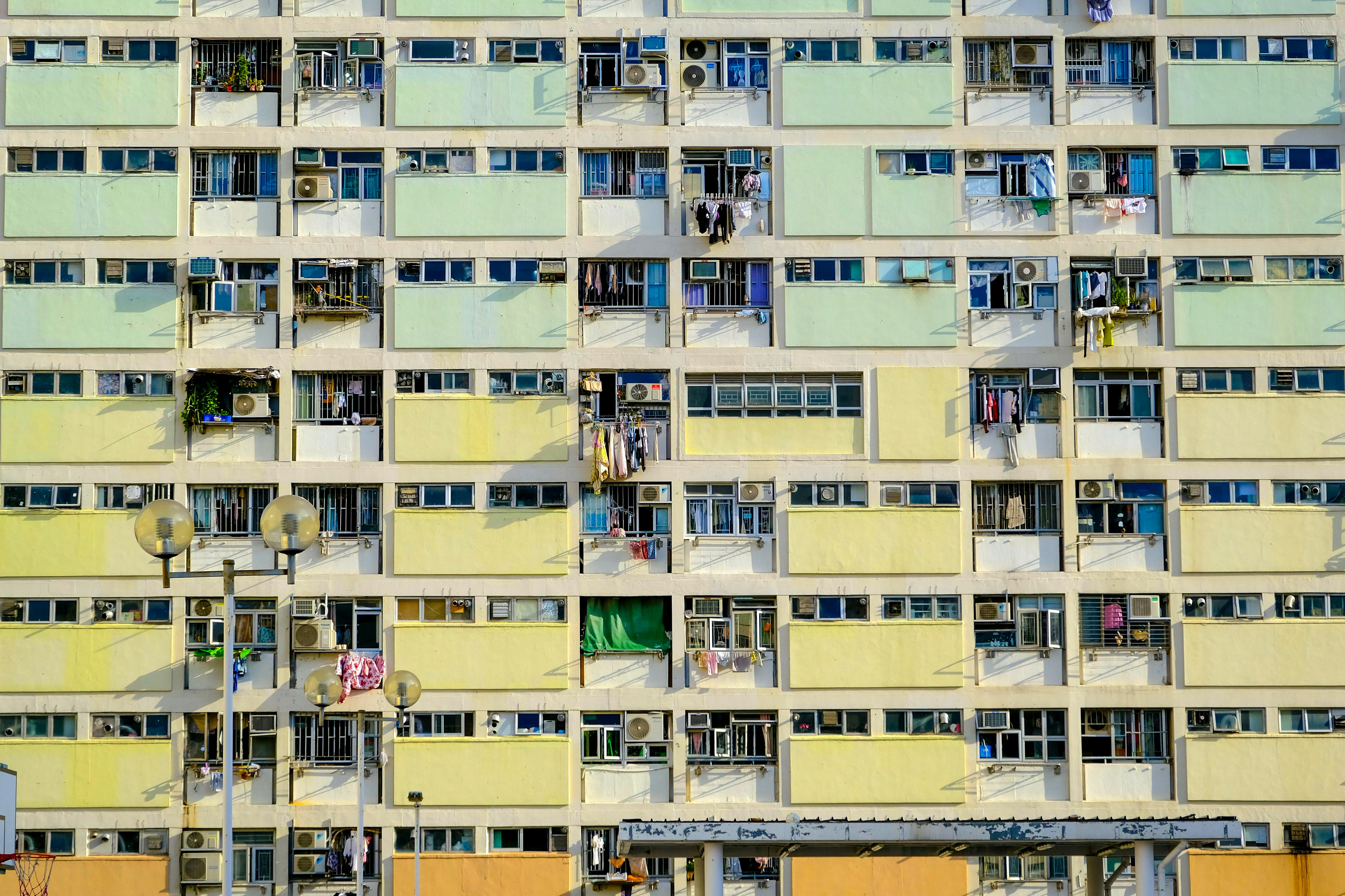 Vibrant facade of an urban apartment block with balconies and air conditioners, showing everyday city life.