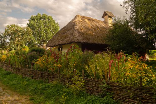 Free Explore traditional Ukrainian architecture with this scenic view of a thatched-roof cottage surrounded by lush gardens. Stock Photo