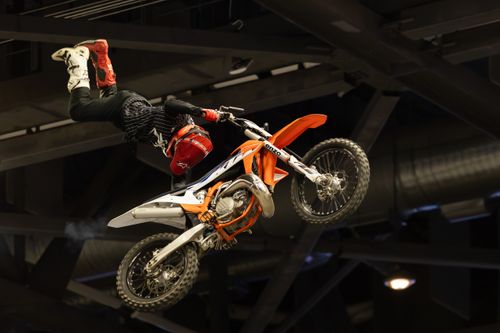 Free Daring motocross stunt performed mid-air indoors by skilled rider. Stock Photo