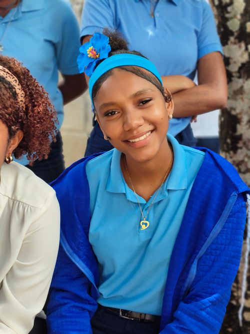 Free Happy teenage girl in a blue school uniform smiling outdoors with friends. Stock Photo