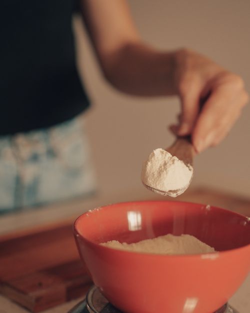 Free Person measuring flour for baking into a red bowl, close-up, indoors. Stock Photo