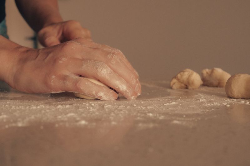 Hands kneading dough on a floured surface, capturing the art of baking.
