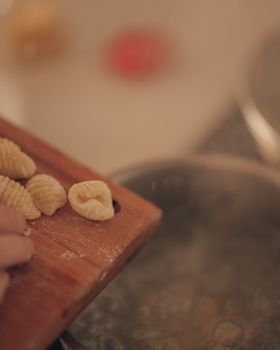 Close-up of handmade pasta being prepared on wooden board for cooking.