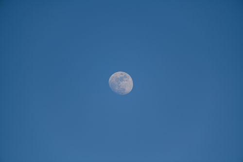Free Close-up of a waxing moon set against a clear blue sky, emphasizing lunar details and tranquility. Stock Photo