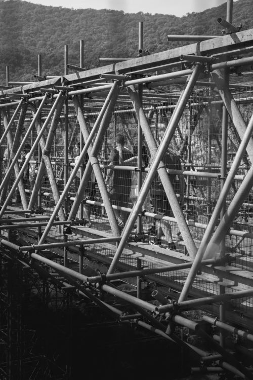 Free Monochrome view of industrial scaffold structure outdoors with workers. Stock Photo