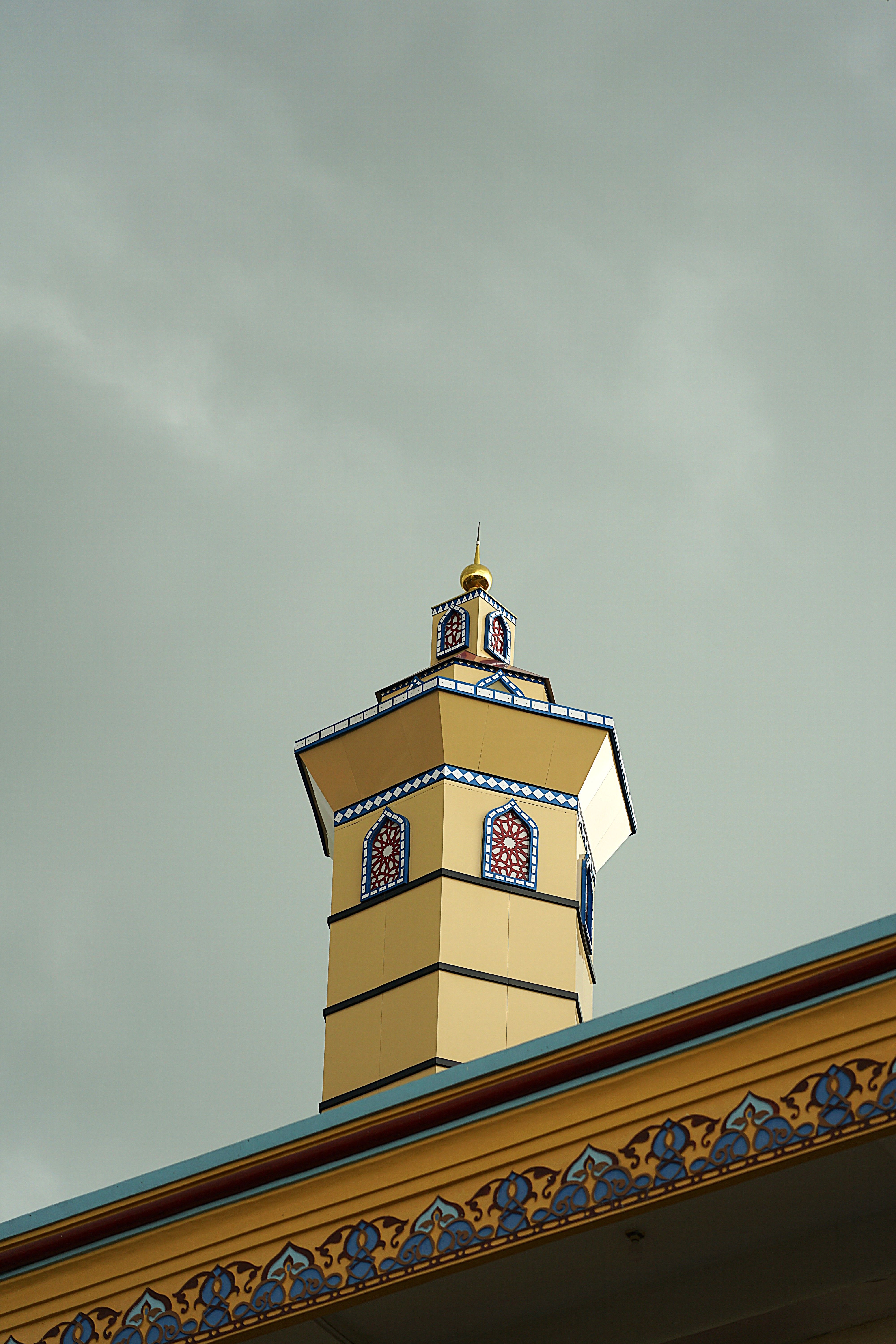 A beautifully detailed Islamic minaret against a cloudy sky in Sukorejo, Jawa Timur.
