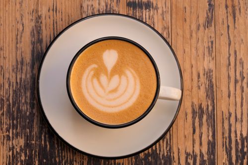 Free Top view of a cappuccino with intricate latte art served on a rustic wooden table. Stock Photo