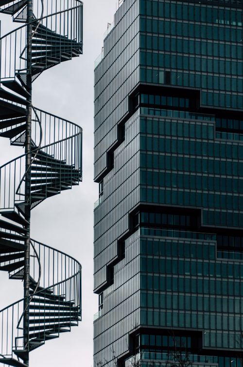 Free Striking contrast between spiral staircases and modern glass skyscraper facade. Stock Photo