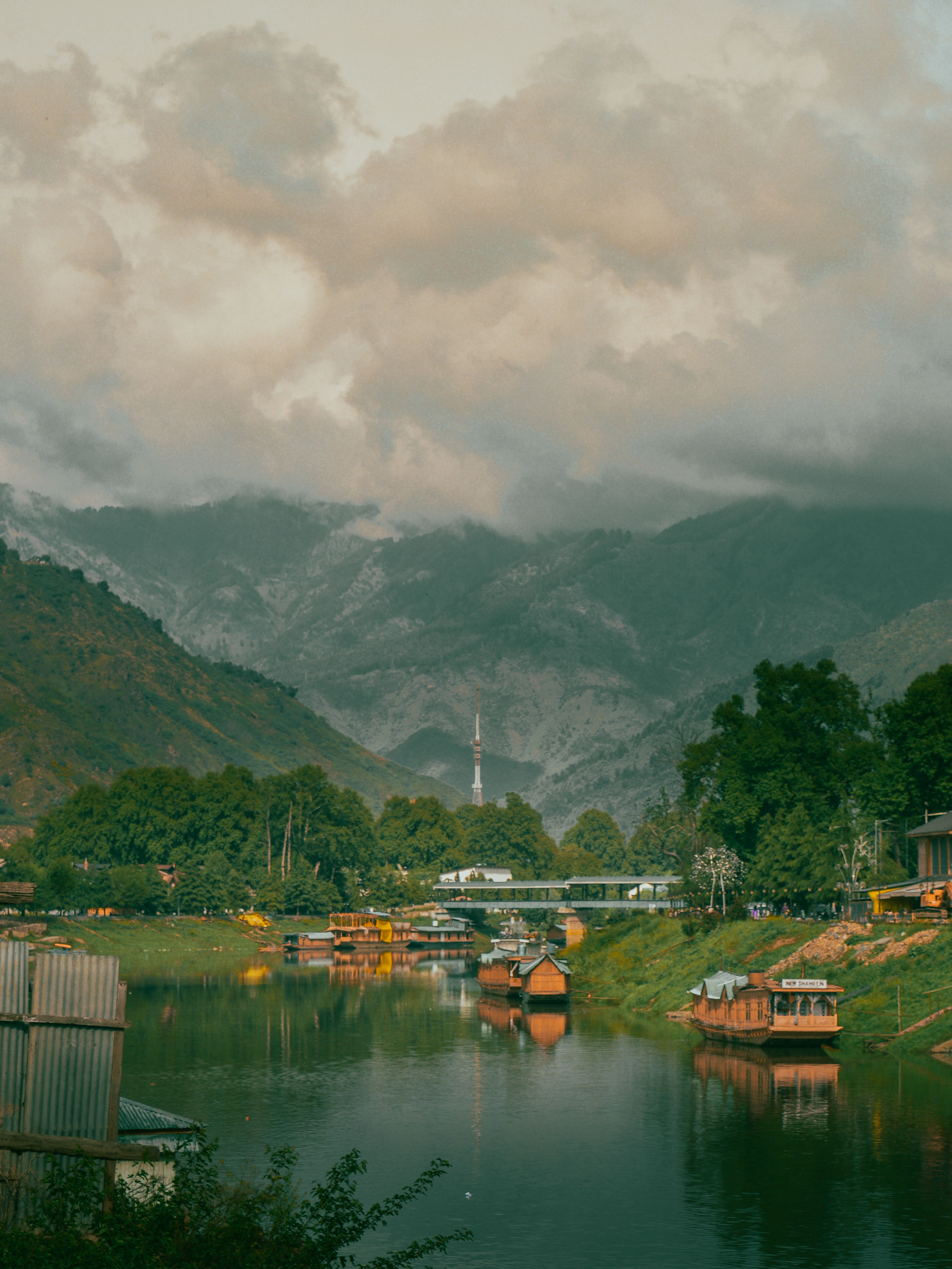 Captivating view of houseboats and mountains on Dal Lake in Srinagar, Kashmir, with dramatic clouds and reflections.