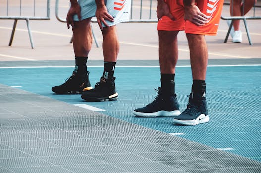 Athletes standing on basketball court, ready for game, focusing on footwear and posture.