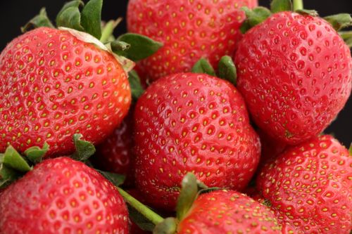 Free A vibrant close-up of fresh, ripe strawberries displaying their rich red color and green leaves. Stock Photo