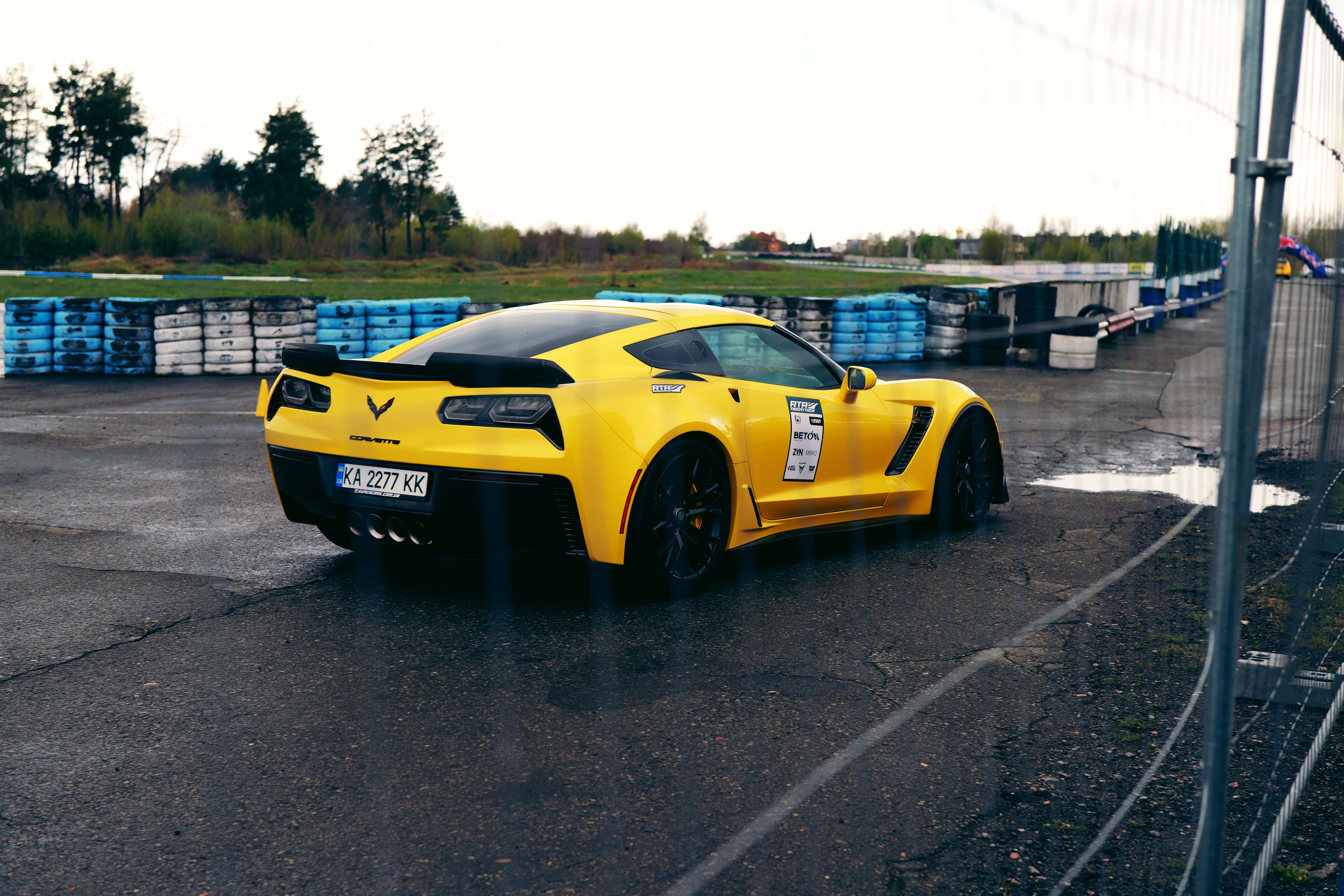 A vibrant yellow sports car on a wet race track in Ukraine, showcasing speed and style.