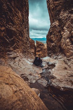 在德克萨斯州大弯国家公园的峡谷溪流中，一名女子正坐在那里探索岩石结构