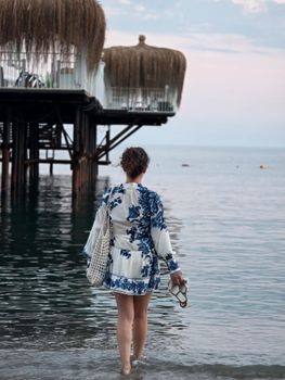 A woman in a floral dress walks along the beach at seaside piers in Alanya, Türkiye.