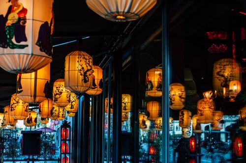 Free Beautiful Asian-style lanterns illuminating against glass windows, creating a warm and reflective ambiance. Stock Photo