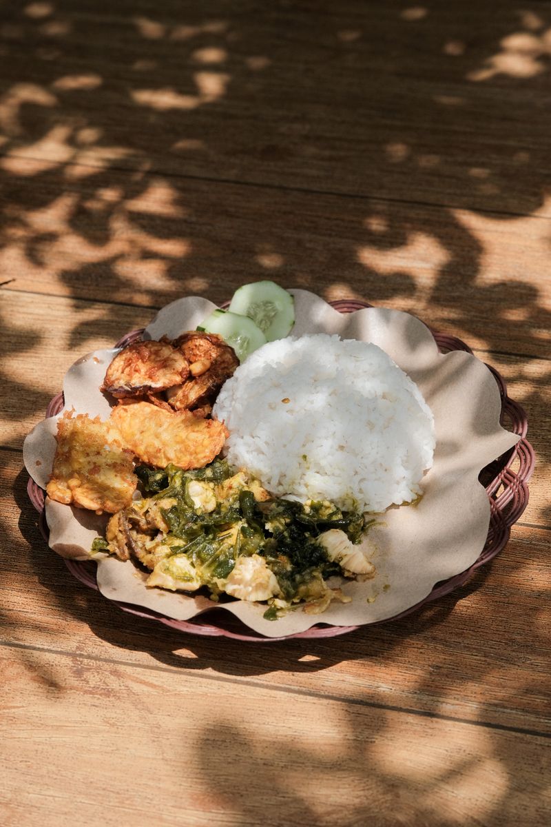 Delicious Indonesian smashed chicken with rice and side dishes, perfect for food enthusiasts.