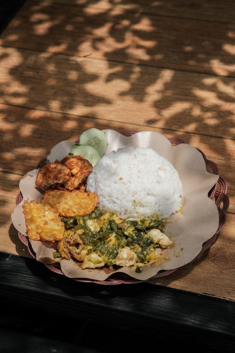 Plate of Ayam Geprek with rice, sambal, and tempeh, traditional Indonesian street food.