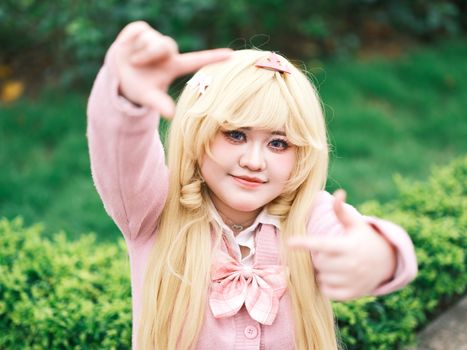 A joyful cosplay enthusiast in a pink costume poses cheerfully outdoors in Vietnam.