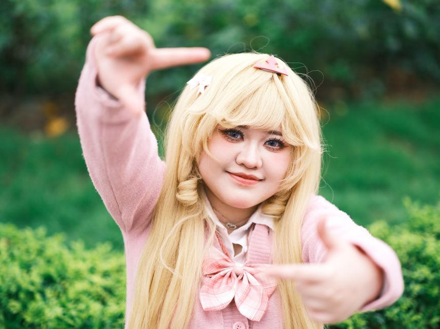 Charming cosplay portrait of a young woman in a garden setting, capturing vibrant style and playful expression.