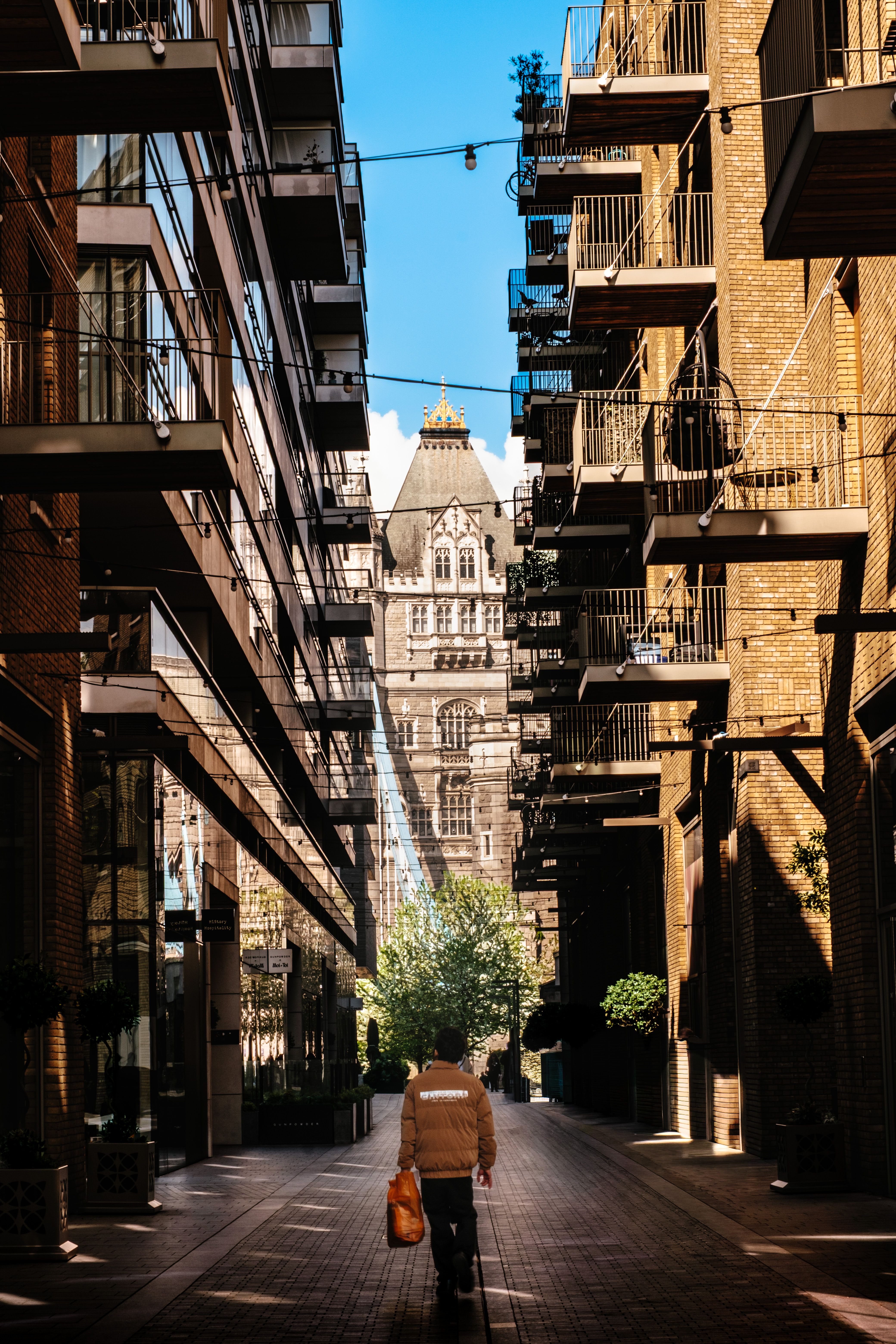 Sunlit alley in London with historic architecture and modern apartments.