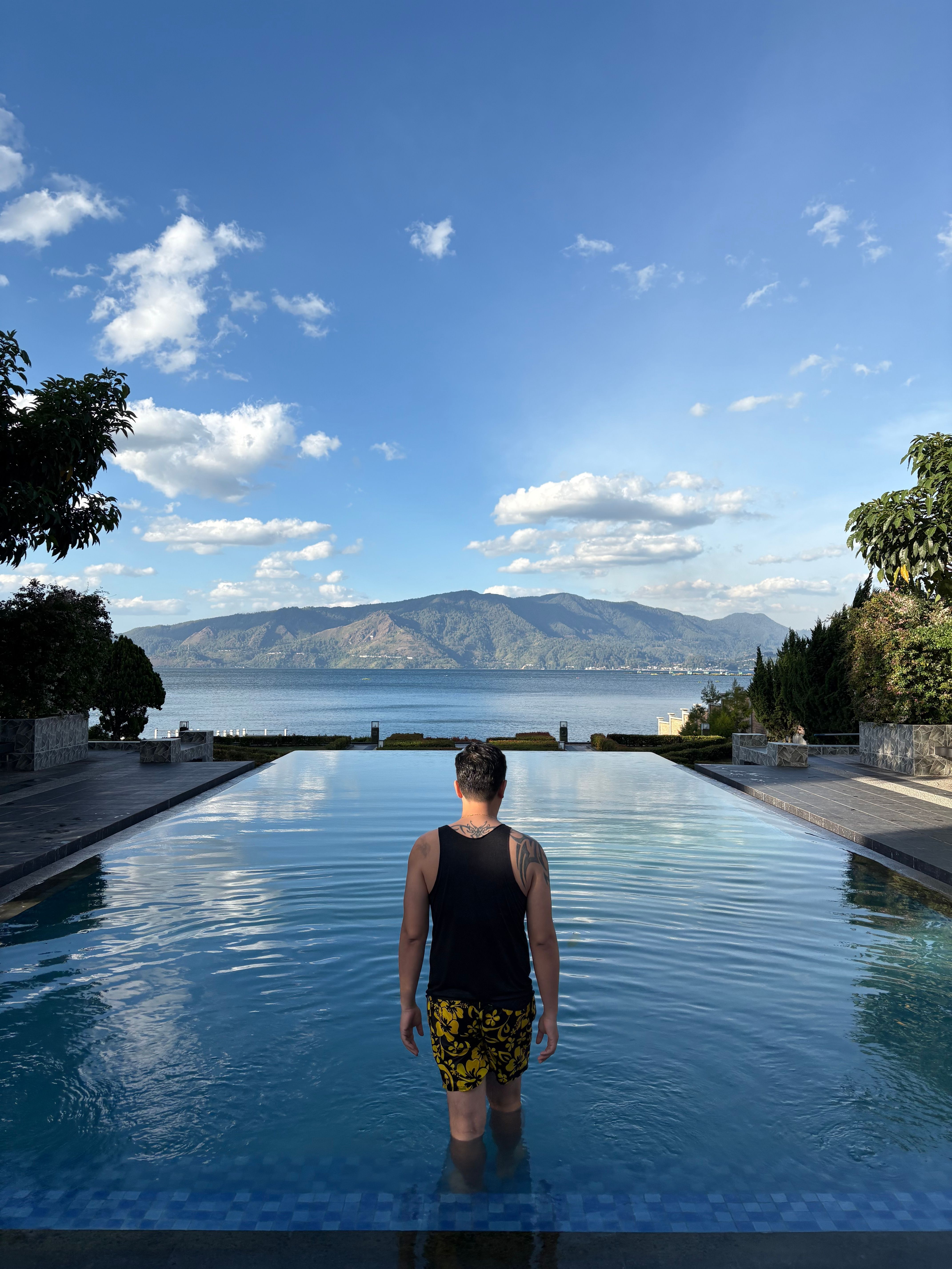 Man in Tropical Infinity Pool Overlooking Mountains · Free Stock Photo