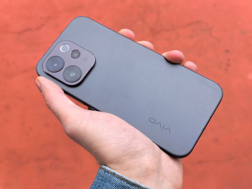 Free A close-up view of a hand holding a sleek smartphone, captured outdoors against a warm backdrop. Stock Photo