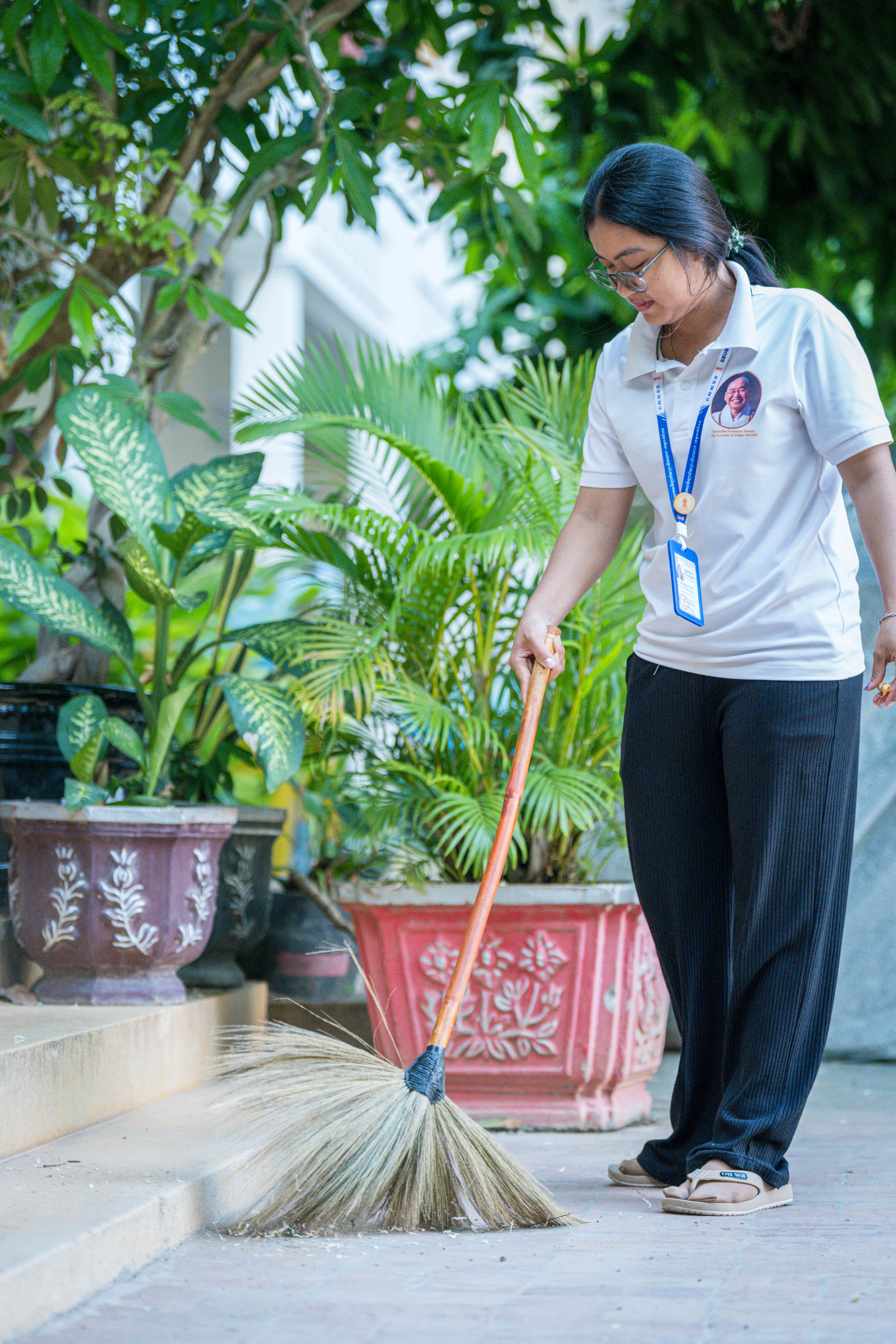 Cambodian Woman Sweeping Garden Pathway · Free Stock Photo