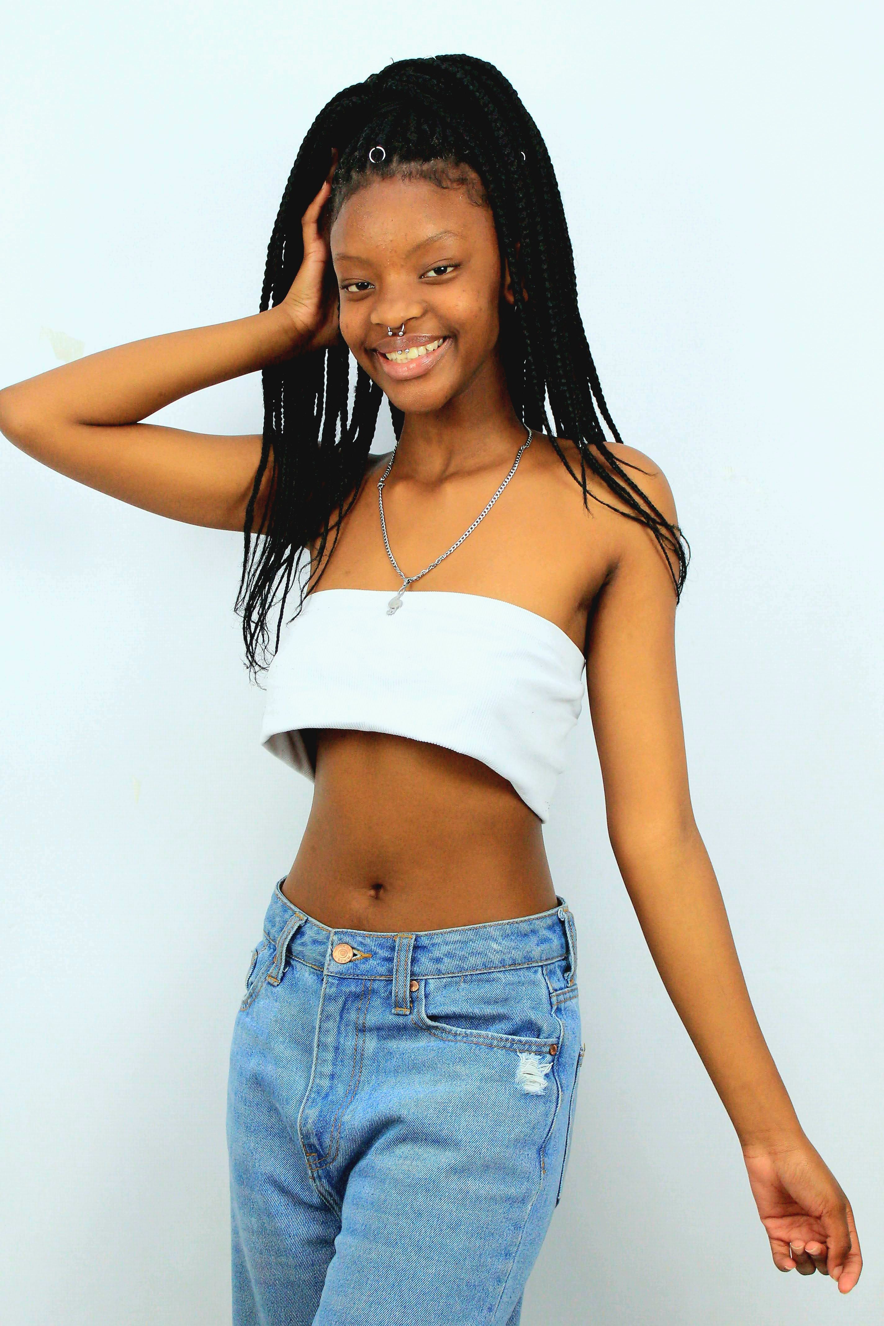 Smiling young woman posing confidently in casual fashion against a light background.