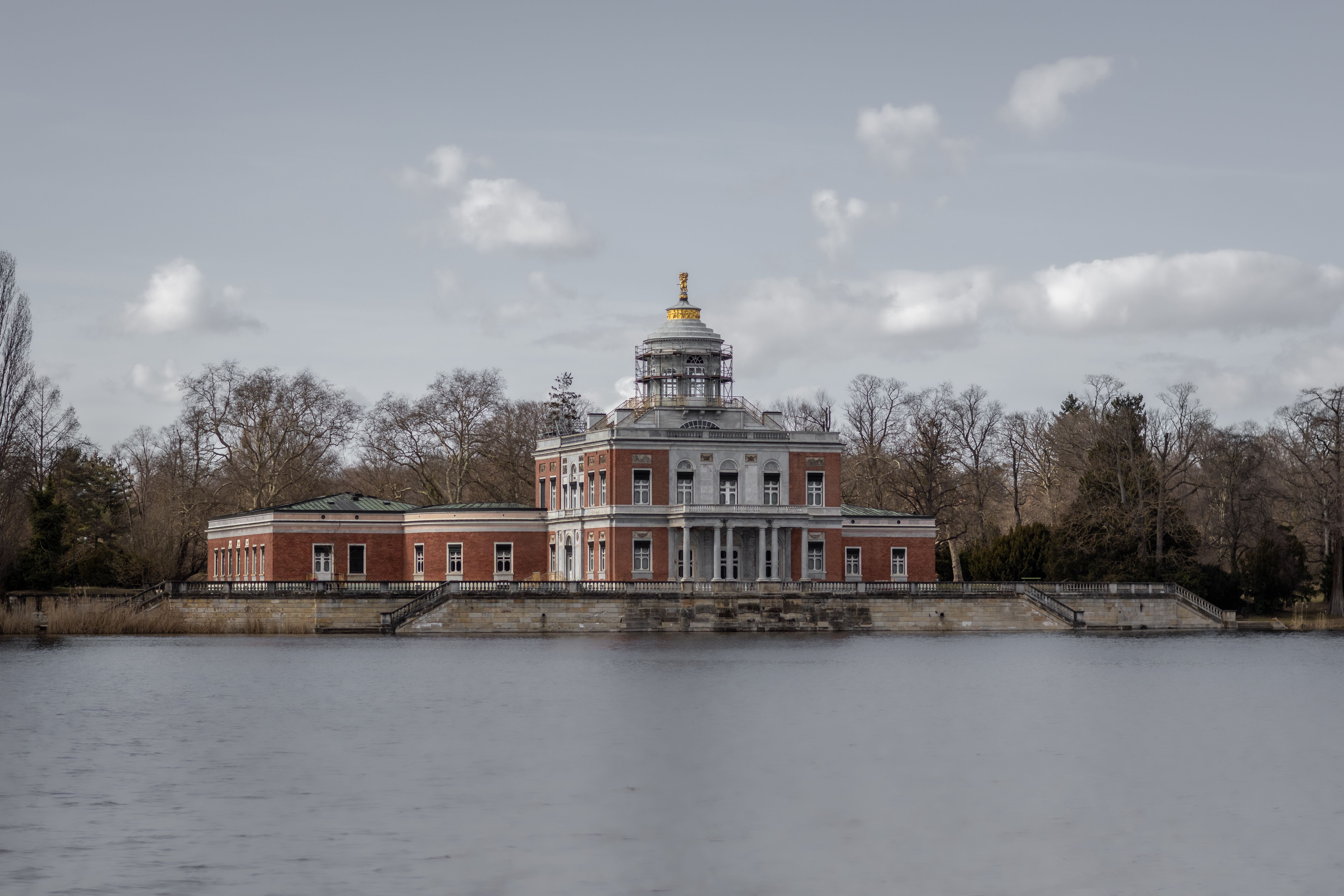 Marmorpalais in Potsdam, Germany, beside a lake under overcast daylight, with red-brick architecture, bare trees and no people
