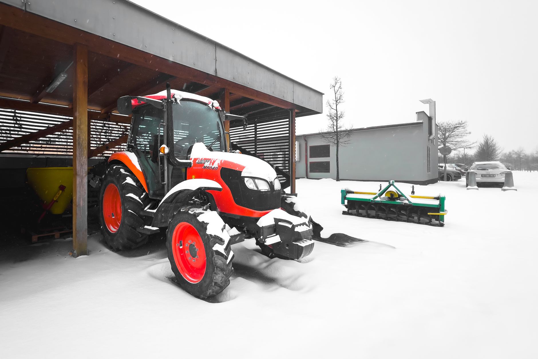 Tractor parked under a shelter in snowy rural setting. Perfect for winter and farming themes.