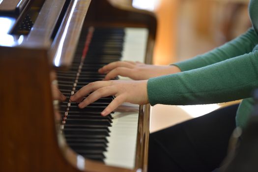 Close-up of hands playing a piano in a warm indoor setting in Vásárosnamény, Hungary.