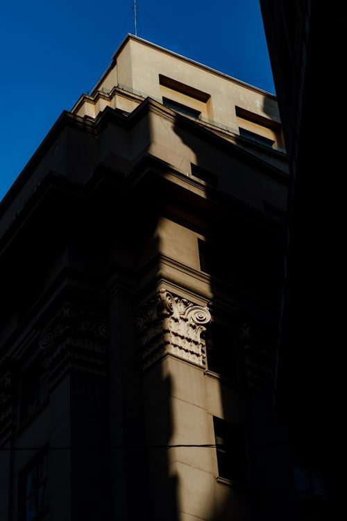 Free A classic building's architectural details in dramatic sunlight and shadow, creating a striking visual contrast. Stock Photo