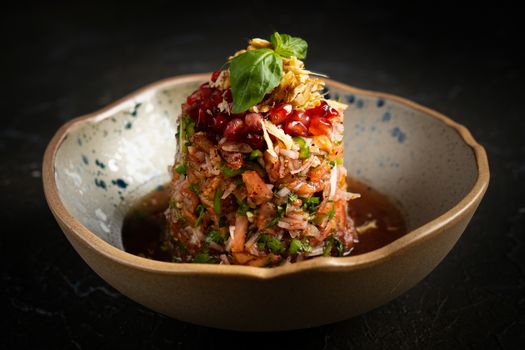 Gourmet salad artfully presented in a ceramic bowl with pomegranate and basil garnish.