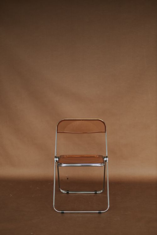 Free A minimalist brown folding chair set against a brown studio backdrop, ideal for design concepts. Stock Photo
