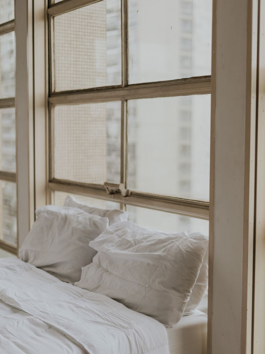 A tranquil, sun-lit bedroom with soft white bedding.