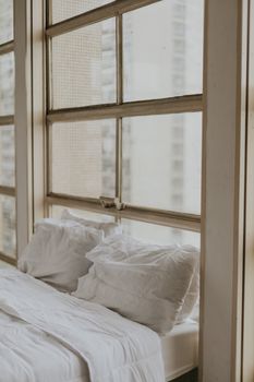 A tranquil bedroom with white bedding and large windows inviting soft daylight. Perfect for relaxation.
